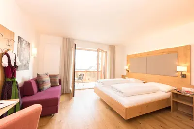 a hotel room with two beds and a purple chair at Panorama Hotel Flora in Villandro