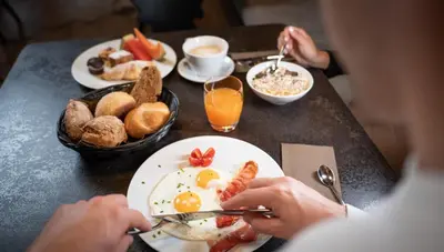 a table with a plate of eggs and breakfast foods at Hotel Wolf in Selva di Val Gardena
