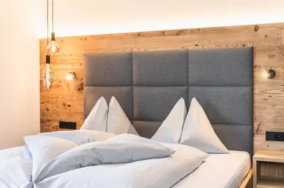 a bedroom with a large bed with white pillows at Hotel Wolf in Selva di Val Gardena