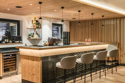 a bar with stools in a room with wood at Hotel Wolf in Selva di Val Gardena