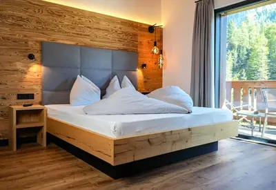 a bedroom with a large bed with white sheets and pillows at Hotel Wolf in Selva di Val Gardena