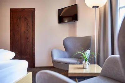 a living room with a chair and a tv at Hotel Walther v.d. Vogelweide Superior in Chiusa