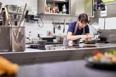 a woman in a kitchen preparing food on a plate at Hotel Walther v.d. Vogelweide Superior in Chiusa
