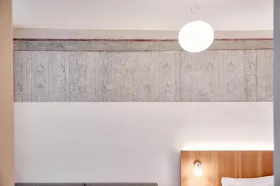 a bedroom with a white wall with a wooden headboard at Hotel Walther v.d. Vogelweide Superior in Chiusa