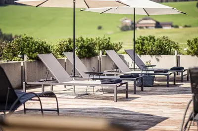 a row of chairs and umbrellas on a patio at Hotel Alpenflora in Castelrotto