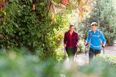 a man and a woman walking through a garden at Hotel Alpenflora in Castelrotto