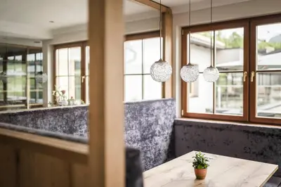 a table in a restaurant with windows and pendant lights at Hotel Alpenflora in Castelrotto
