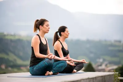 two women sitting in a yoga pose on top of a mountain at Hotel Das Dorner in Lagundo