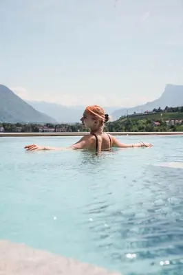 a woman is standing in a body of water at Hotel Das Dorner in Lagundo