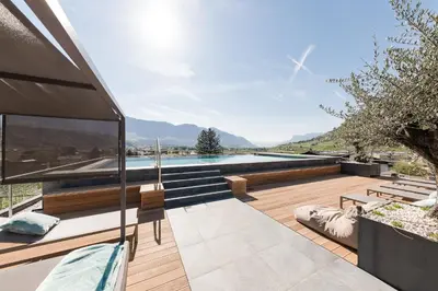 an outdoor patio with a swimming pool and a house at Hotel Das Dorner in Lagundo