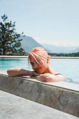 a woman laying in a bath tub next to the water at Hotel Das Dorner in Lagundo