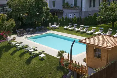a swimming pool with lounge chairs and a house at Albergo al Cervo - Gasthof zum Hirschen in Lagundo