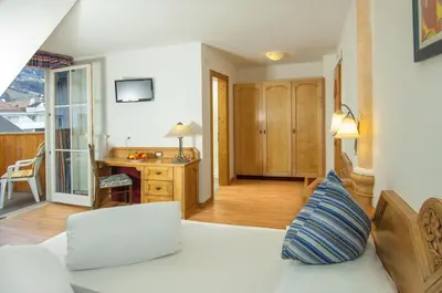 a bedroom with a bed with white sheets and pillows at Albergo al Cervo - Gasthof zum Hirschen in Lagundo