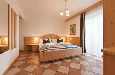 a bedroom with a bed and a desk and a window at Alpin-Residence Amadeus in Siusi