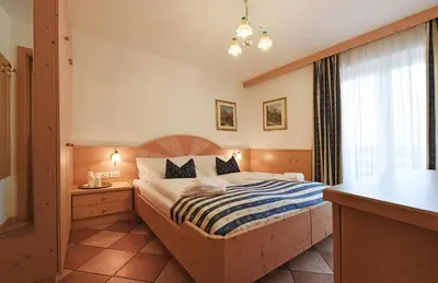 a bedroom with a bed with a blue and white striped blanket at Alpin-Residence Amadeus in Siusi