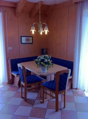 a dining room table with chairs and a vase of flowers at Alpin-Residence Amadeus in Siusi
