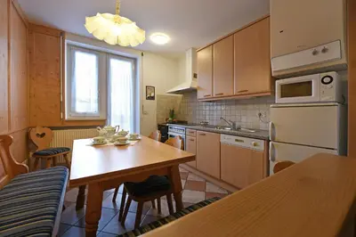 a kitchen with a wooden table and a dining room at Alpin-Residence Amadeus in Siusi
