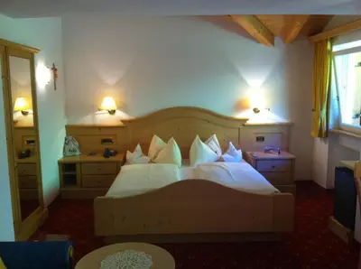 a bedroom with a bed with white sheets and pillows at Garni la Bercia in Selva di Val Gardena