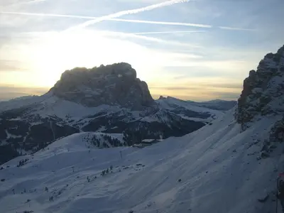a snow covered mountain with the sun setting behind it at Garni la Bercia in Selva di Val Gardena