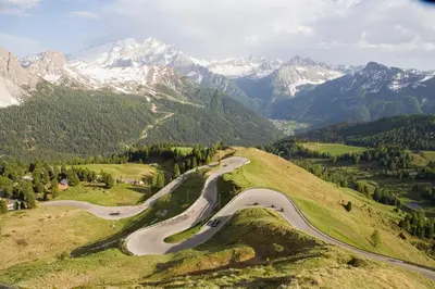 a winding mountain road with snow covered mountains in the background at Das Mondschein in Obereggen