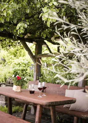 a wooden table with two glasses of wine on it at Pension Haus Tirol in Laion