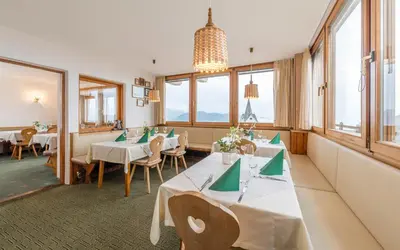 a restaurant with tables and chairs and windows at Pension Haus Tirol in Laion