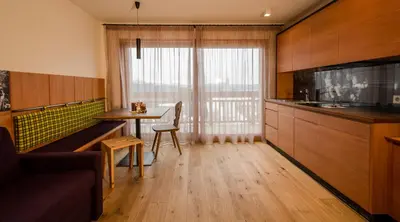 a living room with a table and a kitchen at Pension Haus Tirol in Laion
