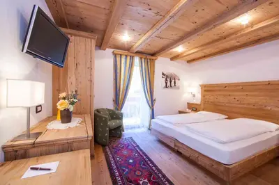a bedroom with a large bed and a flat screen tv at Hotel Corona Krone in Selva di Val Gardena