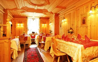 a restaurant with tables and chairs in a room at Hotel Corona Krone in Selva di Val Gardena