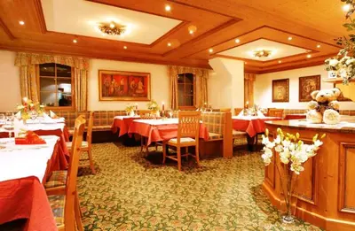 a restaurant with tables and chairs with red table cloth at Hotel Corona Krone in Selva di Val Gardena