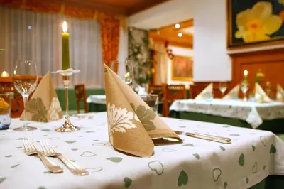 a table with a white table cloth with napkins on it at Hotel Corona Krone in Selva di Val Gardena
