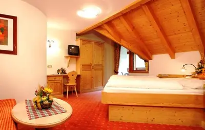 a bedroom with a bed and a table in a room at Hotel Corona Krone in Selva di Val Gardena