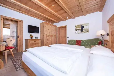 a bedroom with two white beds and a television at Hotel Corona Krone in Selva di Val Gardena