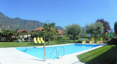 a swimming pool with yellow chairs and a house at Hotel Stamserhof in Andrian