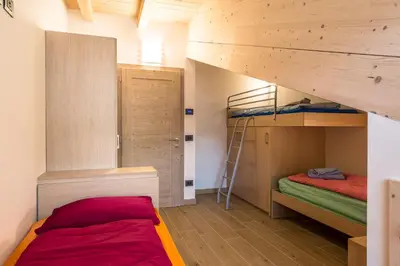 a bedroom with a bed with a wooden headboard and a window at Attico Elbetina in Campitello di Fassa