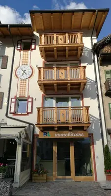 a building with a balcony and a clock on it at Attico Elbetina in Campitello di Fassa