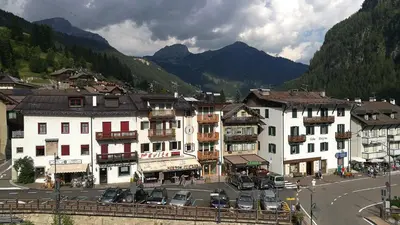 a group of buildings in a town with mountains at Attico Elbetina in Campitello di Fassa