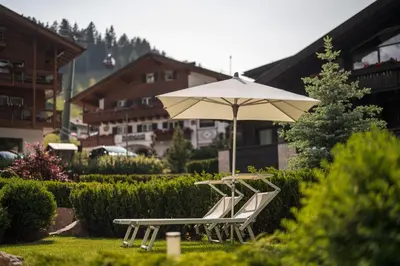 two chairs and an umbrella in a yard at Arya Alpine Lodge in Selva di Val Gardena