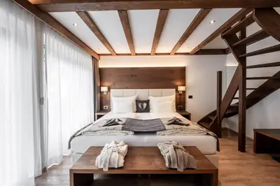 a bedroom with a large bed and a staircase at Arya Alpine Lodge in Selva di Val Gardena