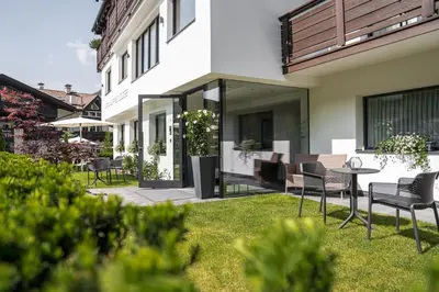 a house with a yard with chairs and a table at Arya Alpine Lodge in Selva di Val Gardena