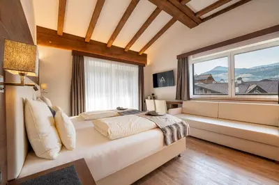 a bedroom with a bed and a large window at Arya Alpine Lodge in Selva di Val Gardena