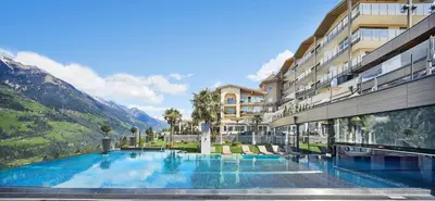 a hotel with a swimming pool in front of a building at Hotel Das Sonnenparadies in Schenna