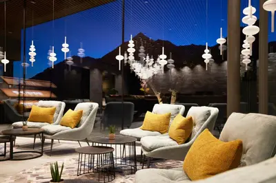 a lobby with chairs and tables and a chandelier at Hotel Das Sonnenparadies in Schenna