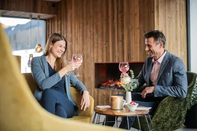 a man and woman sitting at a table drinking wine at K1 Mountain Chalet - Luxury Apartements in Brunico