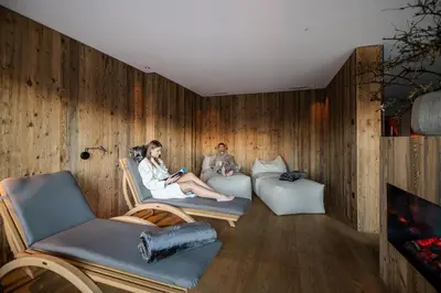 two people sitting on chairs in a room with wooden walls at K1 Mountain Chalet - Luxury Apartements in Brunico