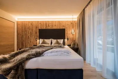 a bedroom with a large bed and a large window at K1 Mountain Chalet - Luxury Apartements in Brunico