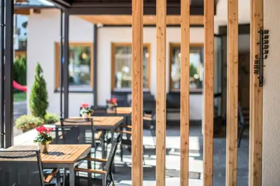 a row of wooden tables and chairs on a patio at Hotel Sterzinger Moos in Vipiteno