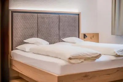 two beds in a room with white sheets and pillows at Hotel Sterzinger Moos in Vipiteno