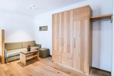 a large wooden cabinet in a room with a couch at Hotel Sterzinger Moos in Vipiteno