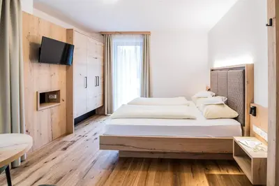 a bedroom with two beds and a flat screen tv at Hotel Sterzinger Moos in Vipiteno